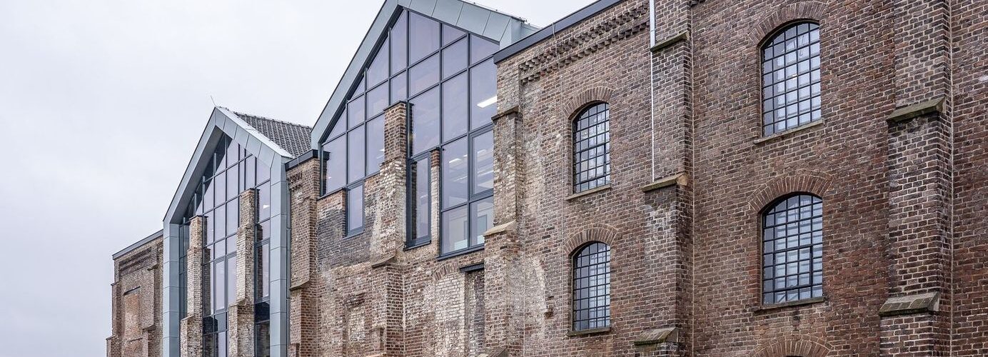 Historic brick industrial building with a modern glass extension